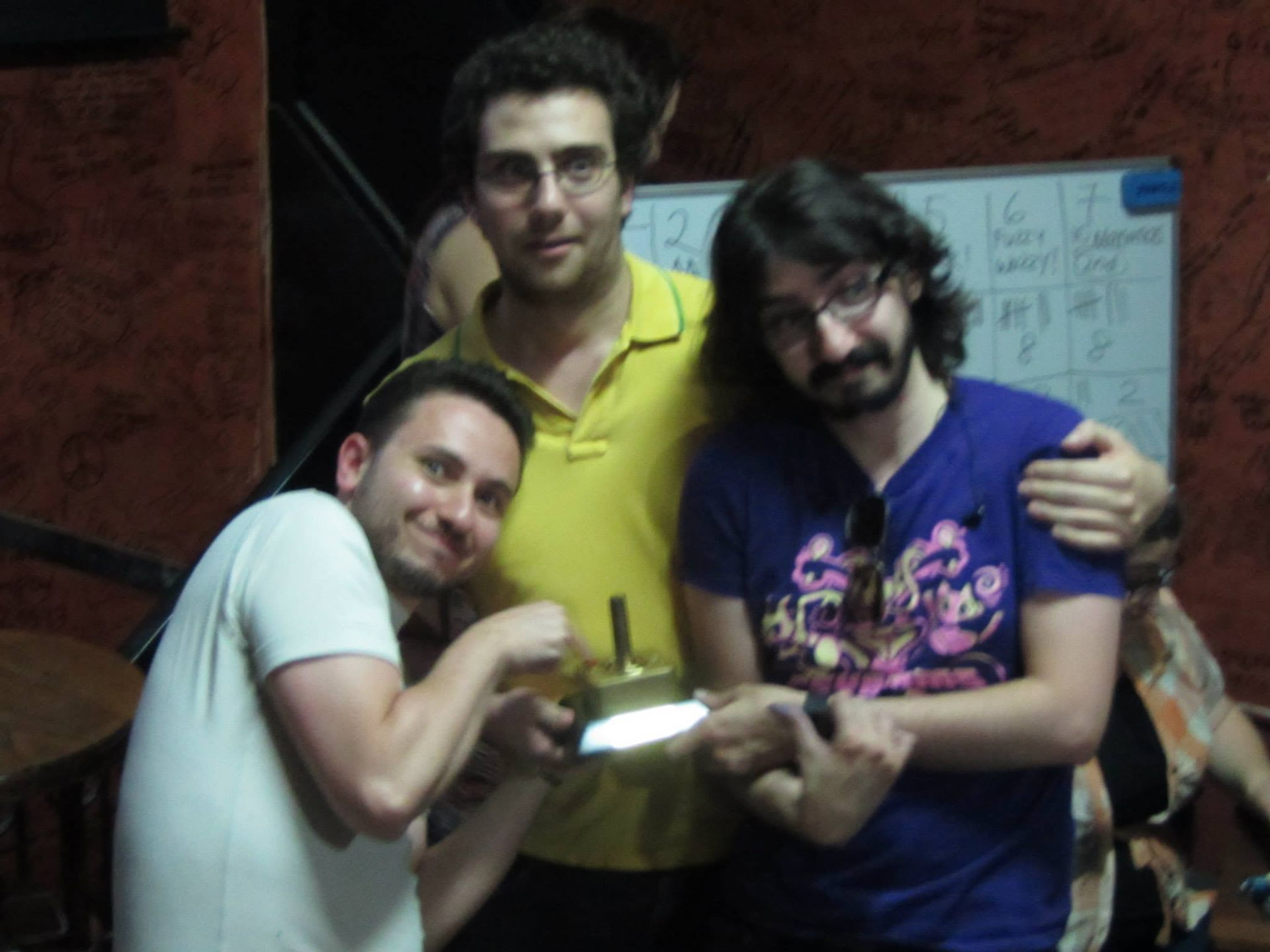 Three people posing together, holding a small gold-coloured object